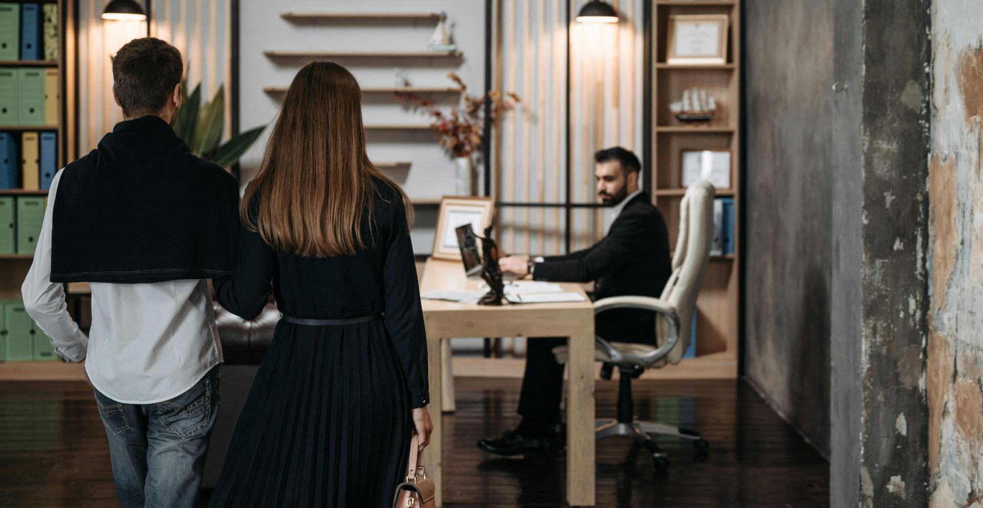 A couple approaches a lawyer in a contemporary office setting for a professional consultation.